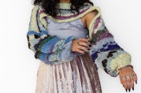 a woman wearing a knitted sweater and pleated skirt